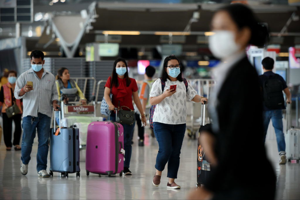 Air Travelers Wear Masks as a Precaution against Covid-19 Bangkok, Thailand - February 18, 2020: Air travelers wearing masks walk through departures hall of Suvarnabhumi Airport. Thailand has been assessed as a country at risk of Covid-19 outside of China.