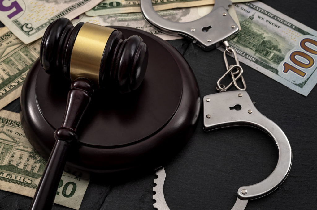 Bail bond system, bailing out of jail and innocent until proven guilty conceptual idea with judge wooden gavel, dollar banknotes and handcuffs Bail bond system, bailing out of jail and innocent until proven guilty conceptual idea with judge wooden gavel, dollar banknotes and handcuffs