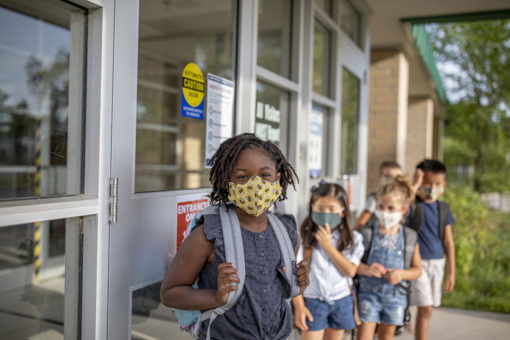 Diverse group of elementary school kids go back to school wearing masks Group of kids return to school during the pandemic.