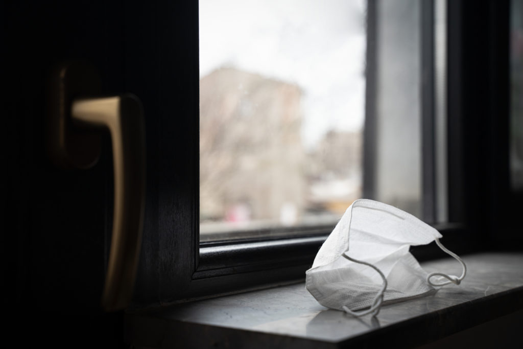 perspective view closeup of medical protection face mask left by the closed window near door handle quarantine concept