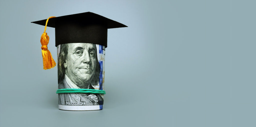 Loan or savings for college. Graduation cap and roll of dollars.