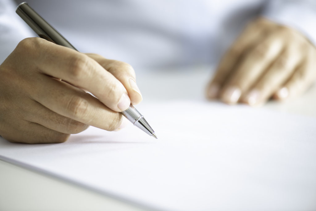 Close up of an unrecognizable businessman signing contract paper.