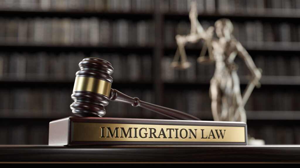 Immigration Law: Judge's Gavel as a symbol of legal system, Themis is the goddess of justice and wooden stand with text word on the background of books.